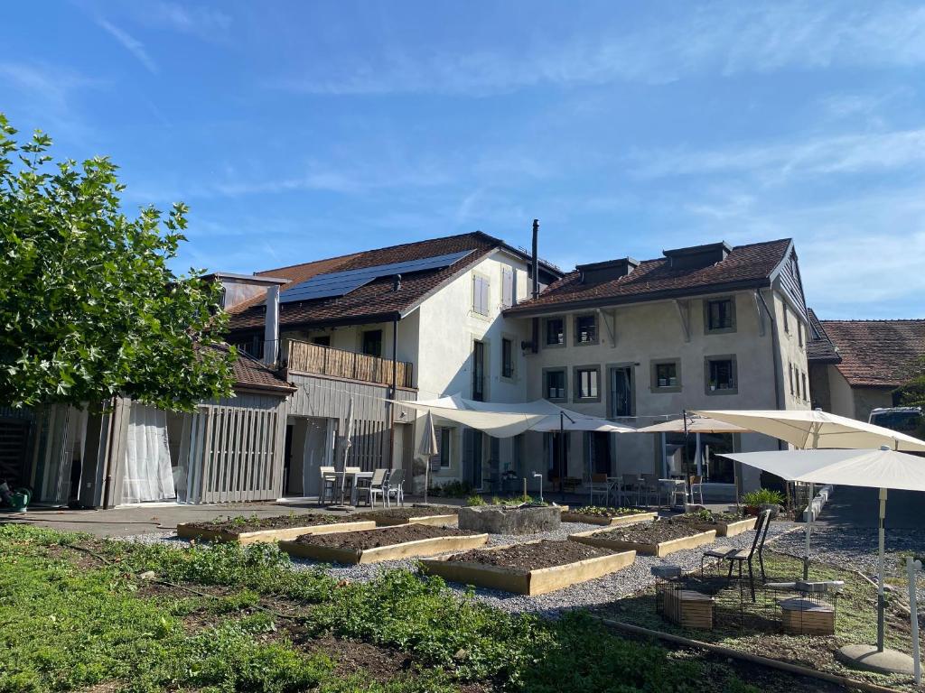 um edifício com mesas e guarda-sóis num quintal em Le Hameau du Montchervet em Puidoux