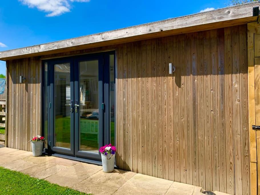 a building with glass doors and flowers in pots at The Old Beauty Room in Paulton