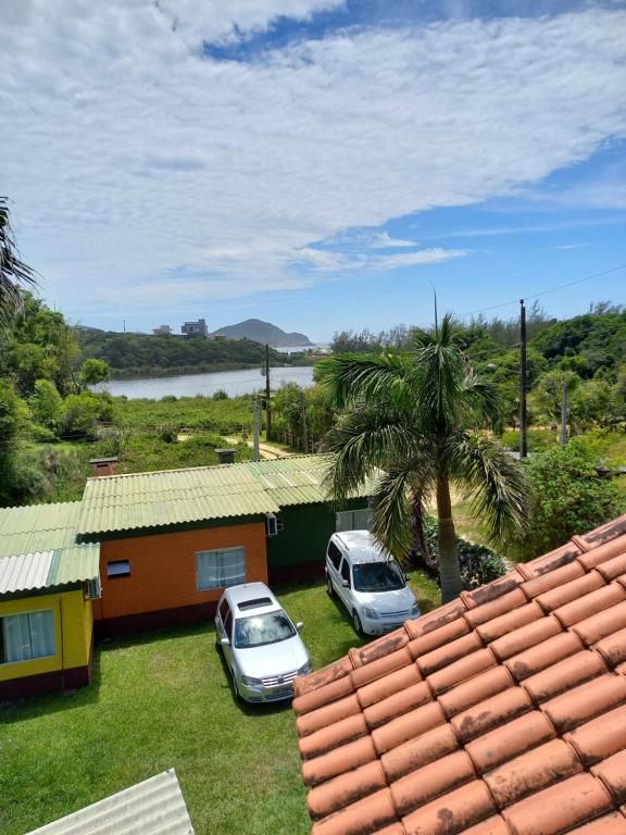 zwei Autos neben einem Haus mit einer Palme in der Unterkunft Canto Rei Cabanas Rosa Sul in Imbituba
