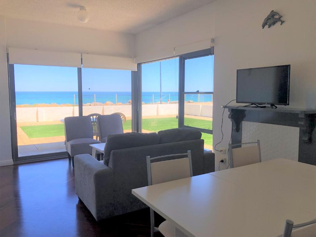 a living room with a couch and a tv and the ocean at The Somerton Beach Retreat in Somerton Park