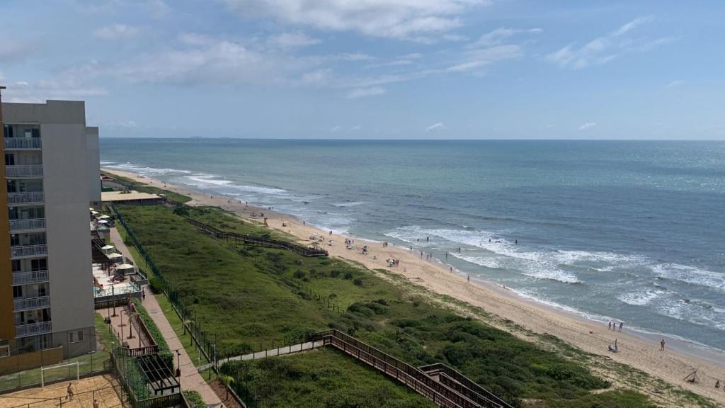 Blick auf den Strand und das Meer mit einem Gebäude in der Unterkunft Apto beira-mar pé na areia in Barra Velha