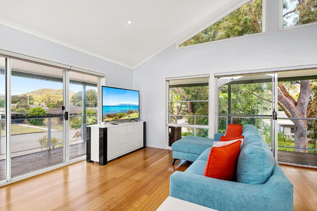 a living room with a blue couch and a tv at Tuncurry Close 1A in Nelson Bay