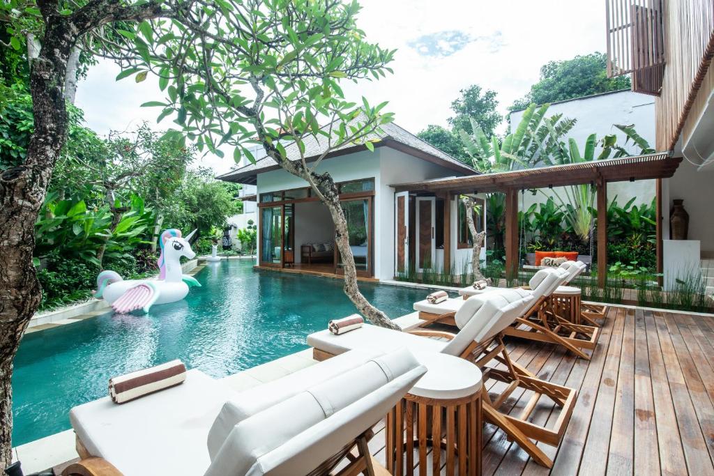 a pool with chaise lounge chairs and an inflatable swan at Paya Paya Villa Seminyak in Seminyak