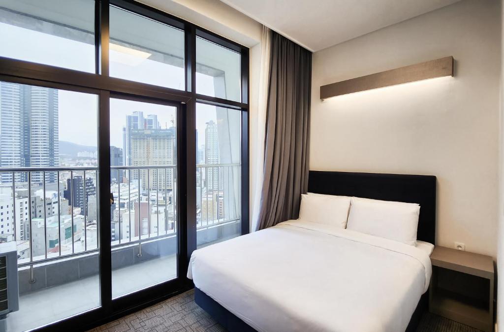 釜山にあるHaeundae Blue Story Hotelのベッドと大きな窓が備わるホテルルームです。