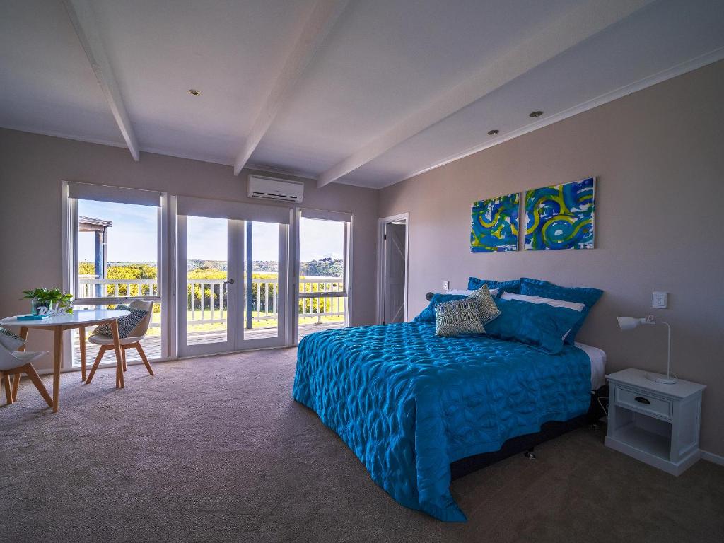 sypialnia z niebieskim łóżkiem oraz stołem i krzesłami w obiekcie 1-bedroom unit with balcony and ocean views! w mieście Smiths Beach