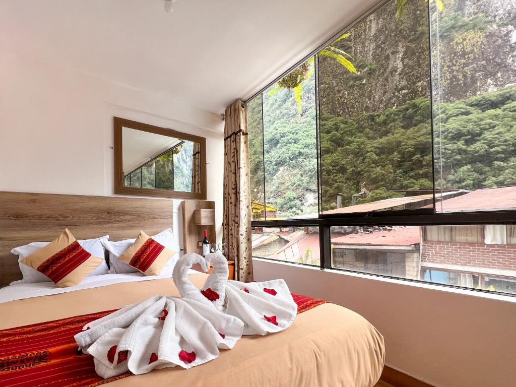 1 dormitorio con 2 toallas de cisne en una cama en Runas Inn Machupicchu en Machu Picchu
