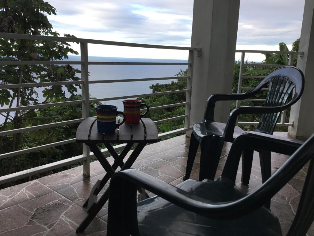 a balcony with two cups and a table and a chair at Abigail's Spectacular 2 bedrooms-Entire Apartment in Tortola Island