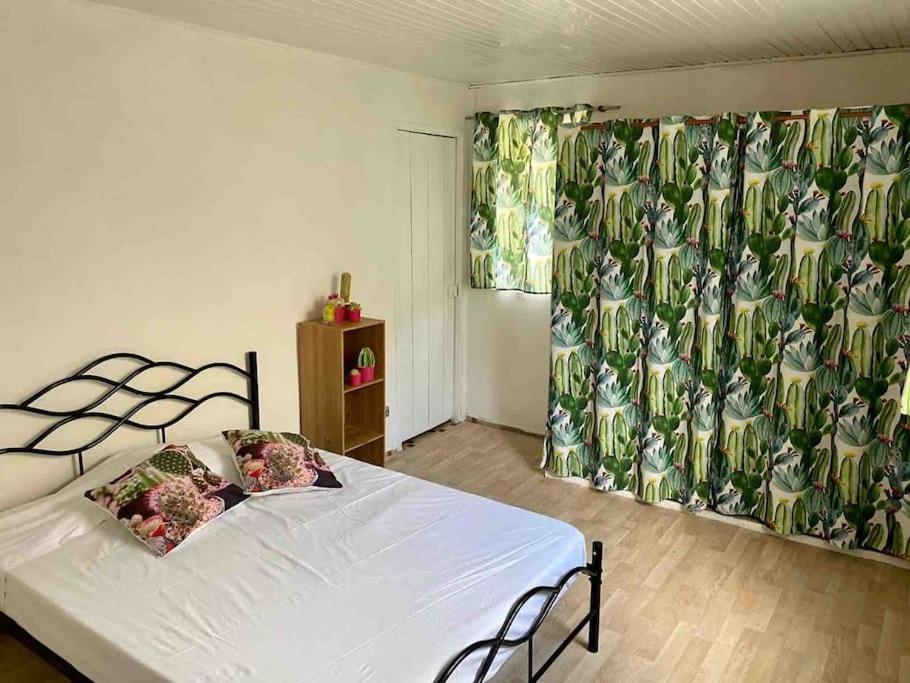 1 dormitorio con 1 cama con sábanas y cortinas blancas en Maison chaleureuse avec terrasse et parking privé en Le Lamentin