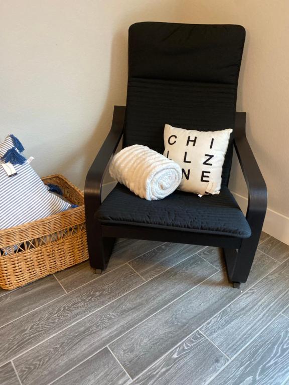 a black chair with a pillow and a basket at Private entrance apartment in Bentonville