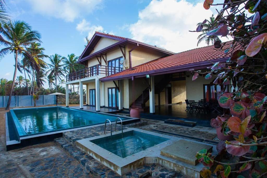 ein Haus mit einem Pool vor einem Haus in der Unterkunft Reef Bungalow Private Villa, 4 bedrooms in Bopitiya