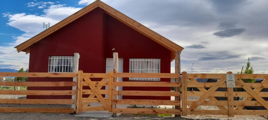 a red barn with a wooden fence in front of it at Cabaña Aike in El Calafate
