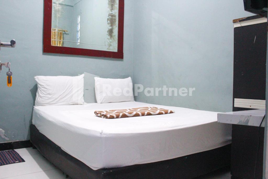 a bed with white sheets and pillows in a room at Snow White Residence near Grogol Mitra RedDoorz in Jakarta