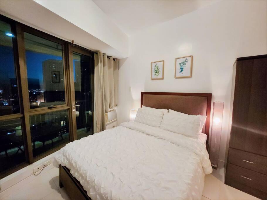 a bedroom with a large bed and a large window at Modern Hotel-type Studio near Greenbelt Netflix 100mbps in Manila