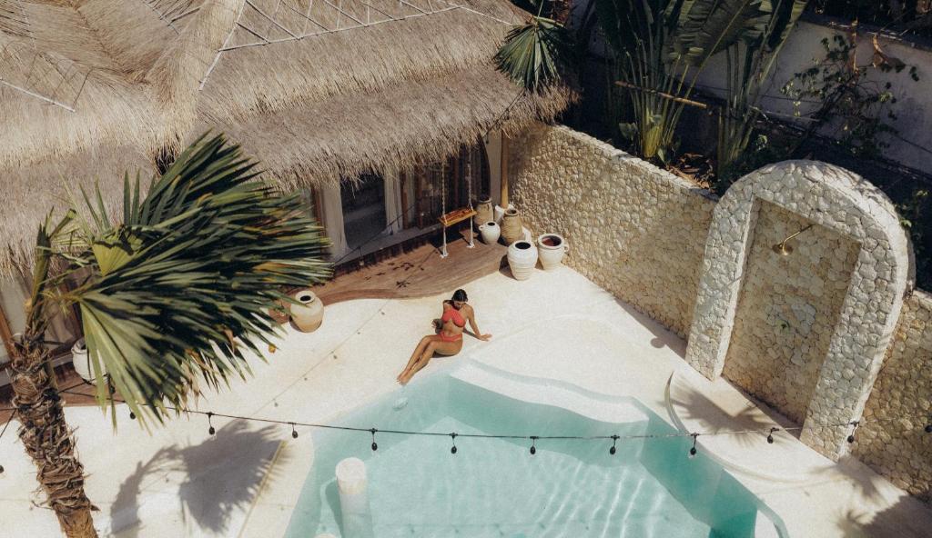 an overhead view of a woman sitting next to a swimming pool at Belajar Bali Boutique Hotel and Retreat in Canggu