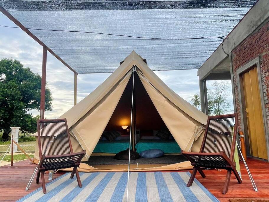 une tente en tipi sur une terrasse avec 2 chaises dans l'établissement Rembulan Escape - beachfront bell tent (no 1), à Kampung Penarik