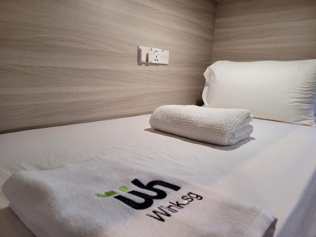 Una cama con una manta blanca y almohadas. en Wink at Upper Cross Street, en Singapur