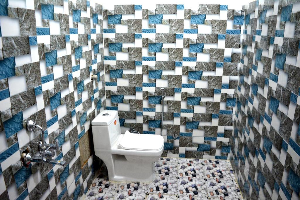 a bathroom with a toilet and a tile wall at Rani Homestay Khajuraho in Khajurāho