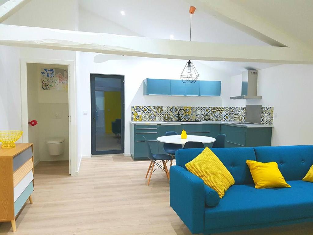 a living room with a blue couch and a kitchen at Les Granges de Jules in Lafitte-Vigordanne