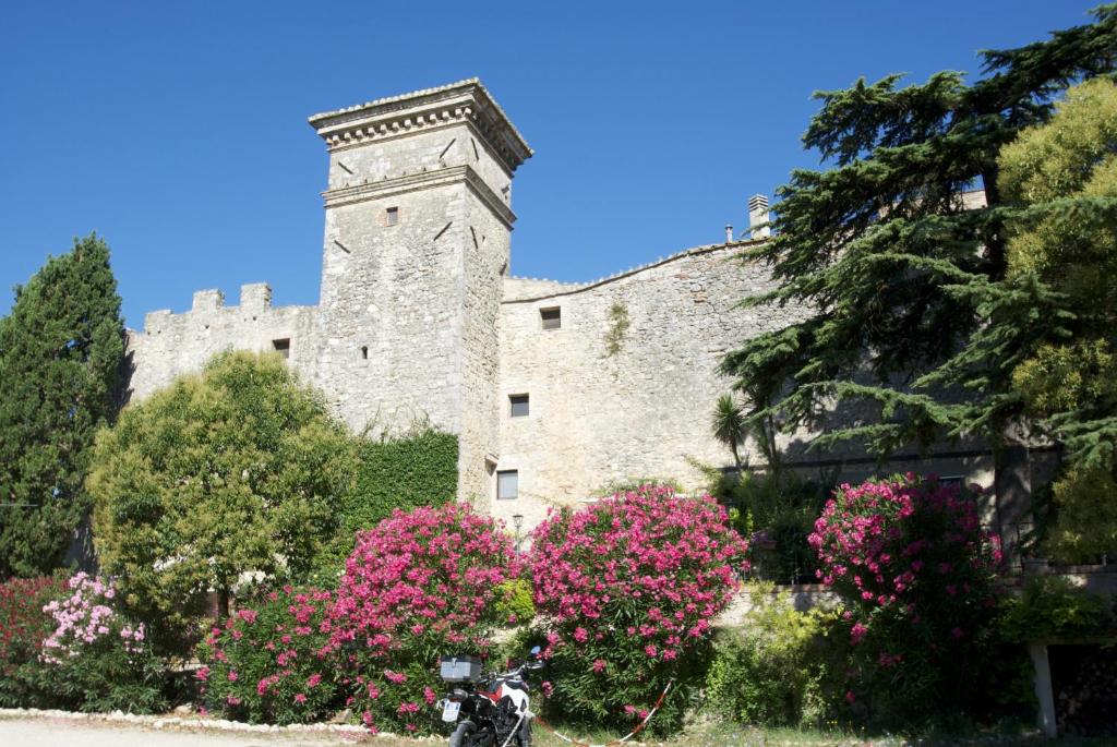 un château avec des fleurs roses en face d'un bâtiment dans l'établissement Torre Sangiovanni Albergo e Ristorante da Rosary, à Todi