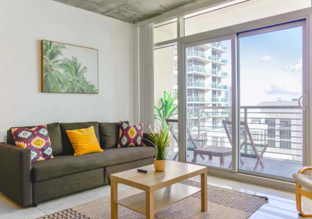 a living room with a couch and a large window at Two Bedroom Apartment with Pool At Midblock Miami in Miami