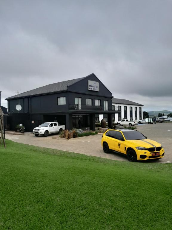 un'auto gialla parcheggiata di fronte a un edificio nero di Protea Hotel by Marriott Harrismith Montrose a Harrismith