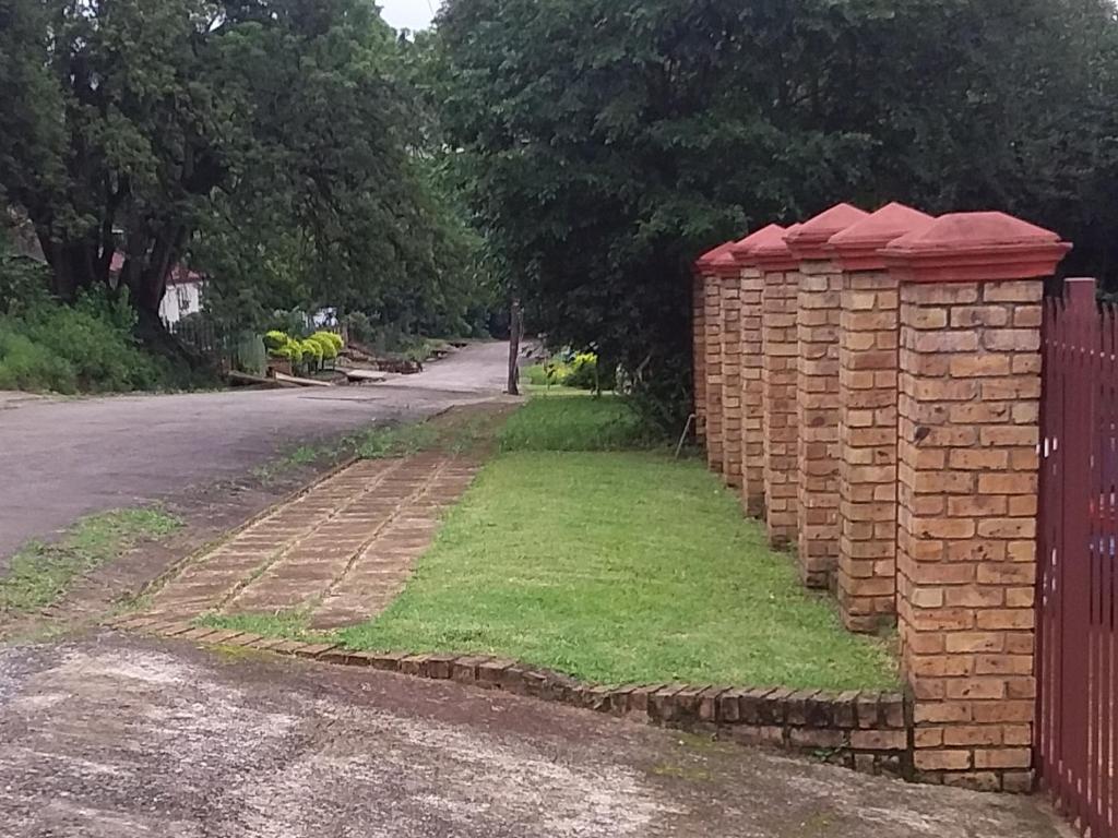 a brick fence on the side of a road at Amaroks self catering units in Sabie