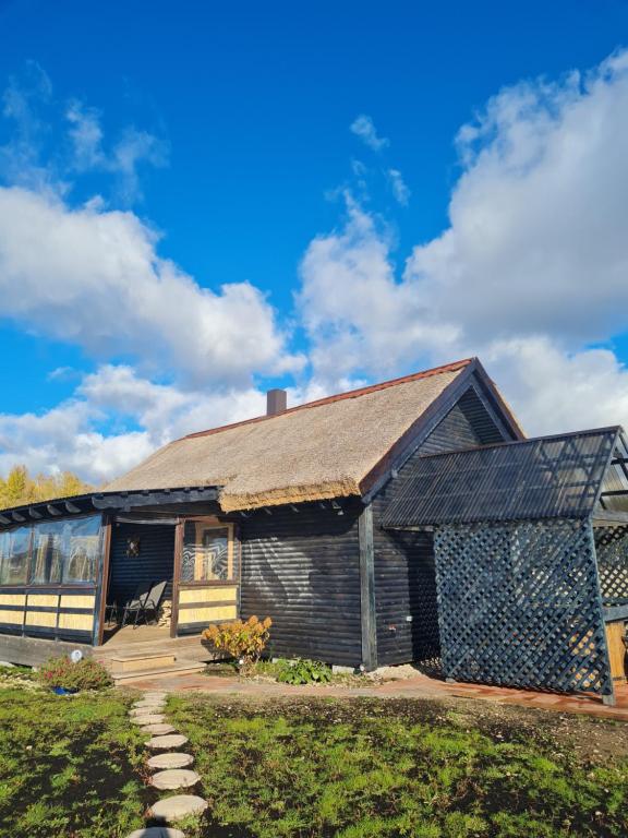 uma casa de madeira com um telhado de gambrel em Brīvdienu māja Pakavi em Skulte