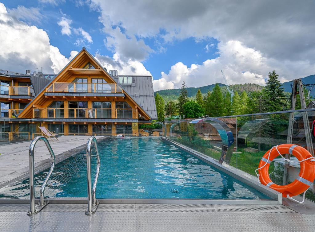 uma piscina com uma casa e um edifício em VisitZakopane - Royal Resort Wellness & SPA em Zakopane