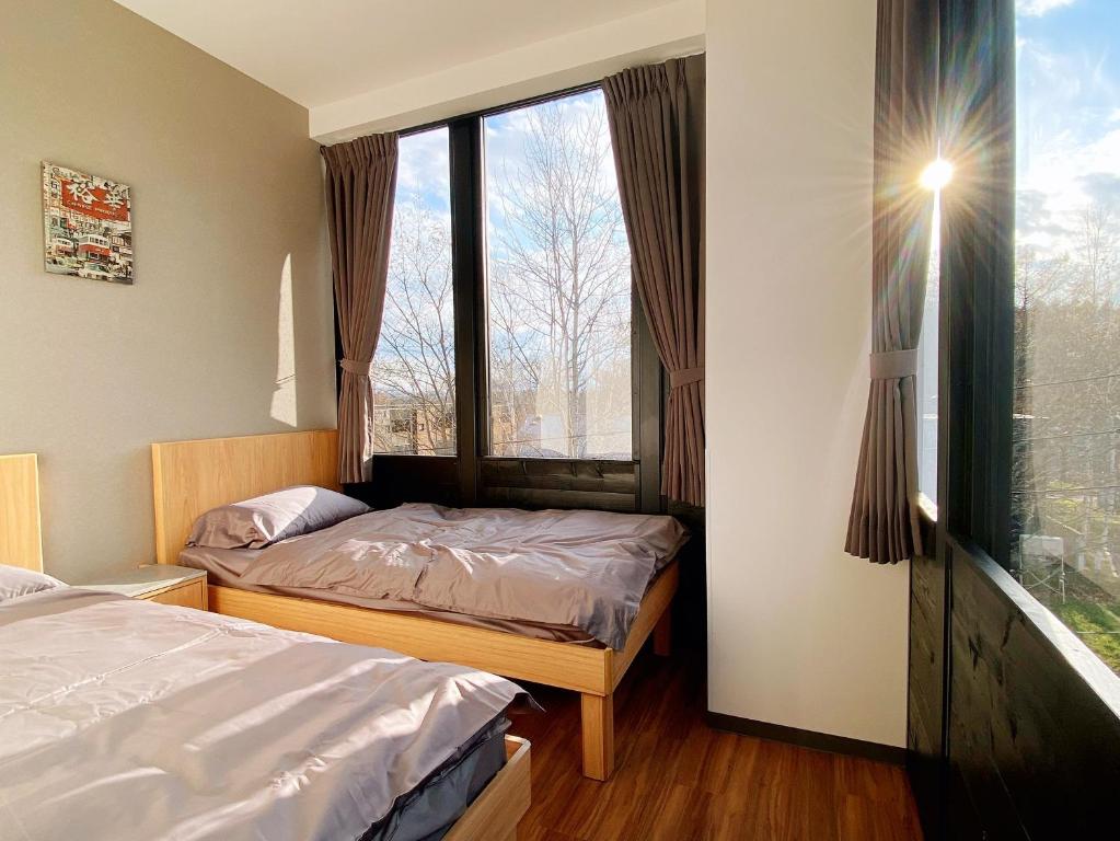 a bedroom with two beds and a large window at Q FOX BLACK DIAMOND HOTEL in Niseko