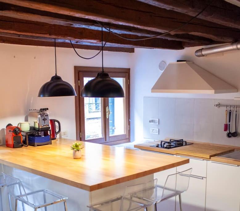 a kitchen with a large wooden counter top with chairs at Erbe Canal View Private House in Venice
