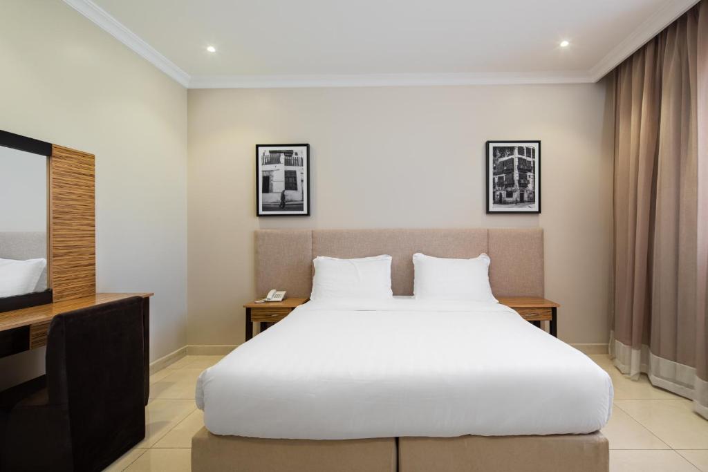 1 dormitorio con 1 cama blanca grande y escritorio en Mirada Purple - Obhur, en Yeda