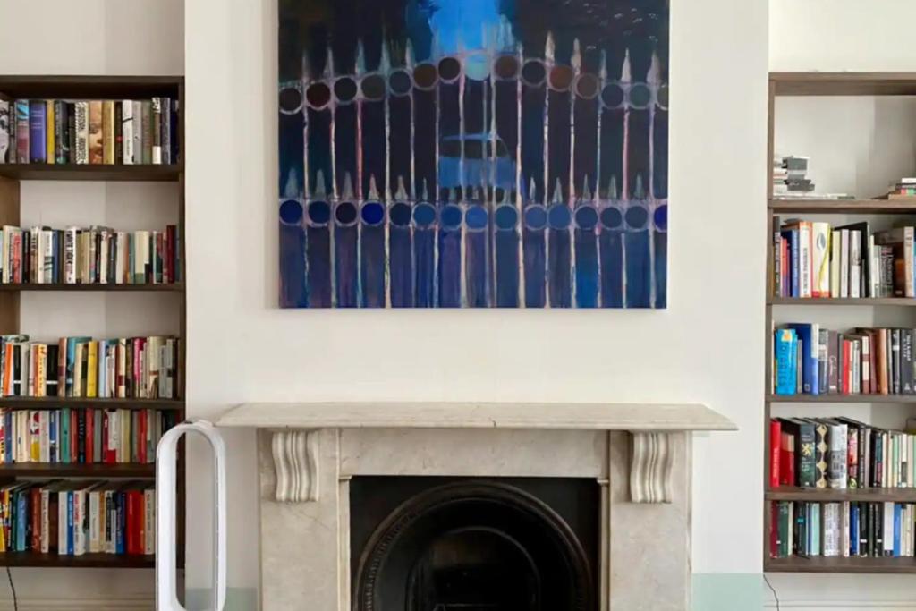 a fireplace in a living room with books at Spacious 2 Bedroom flat in Central London in London