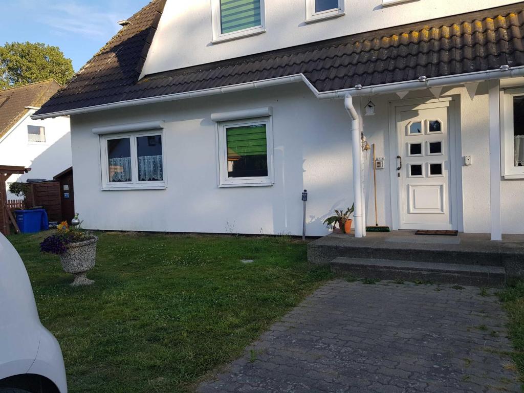 a white house with a door and a grass yard at Ferienwohnung am Teich in Lütow