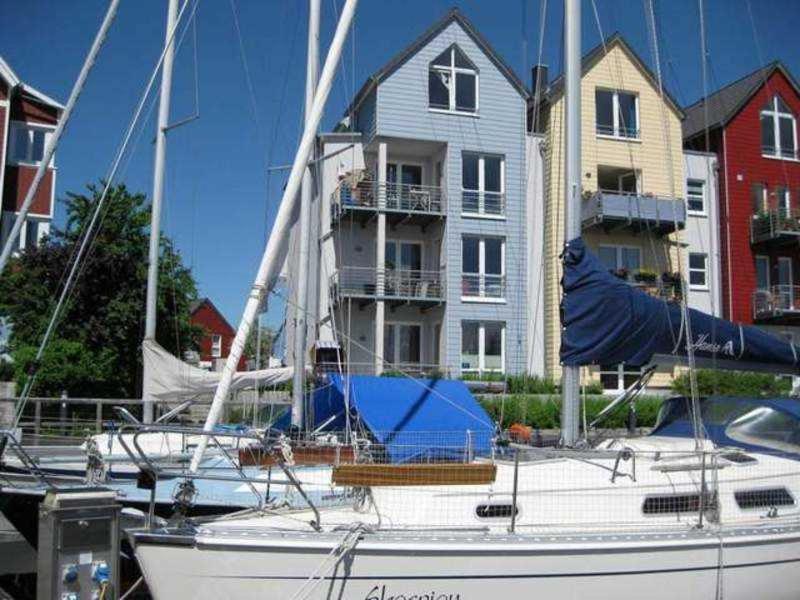 un velero atracado frente a una casa grande en Ferienwohnungen Am Yachthafen, en Greifswald