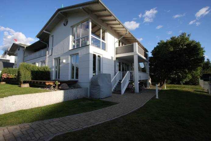 ein großes weißes Haus mit einer Veranda auf einem Rasen in der Unterkunft Kleines Haus am Meer Frank Starkowski in Lubmin