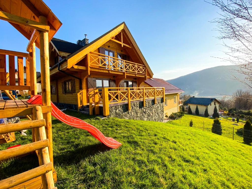 drewniany dom na wzgórzu z czerwoną zjeżdżalnią w obiekcie Góralska Willa Bajka w Międzybrodziu Żywieckim