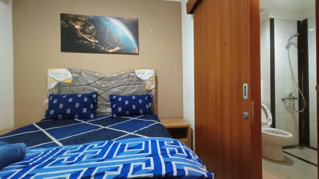 una camera con letto blu e doccia di Mushroom Apartment Grand Kamala Lagoon by Mrs Sewa a Pekayon Satu