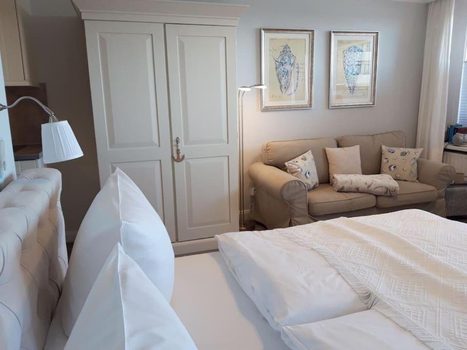een witte slaapkamer met een bed en een bank bij Appartement Nordmuschel in Westerland in Westerland