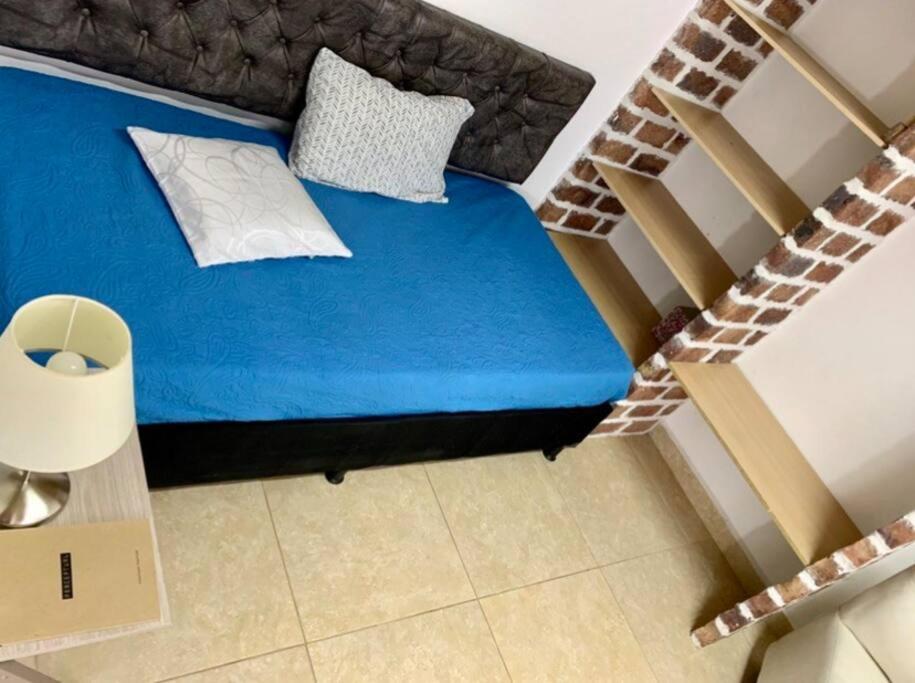 - une petite chambre avec un lit bleu et un escalier dans l'établissement Casa a 650 metros Estación metro la Floresta., à Medellín