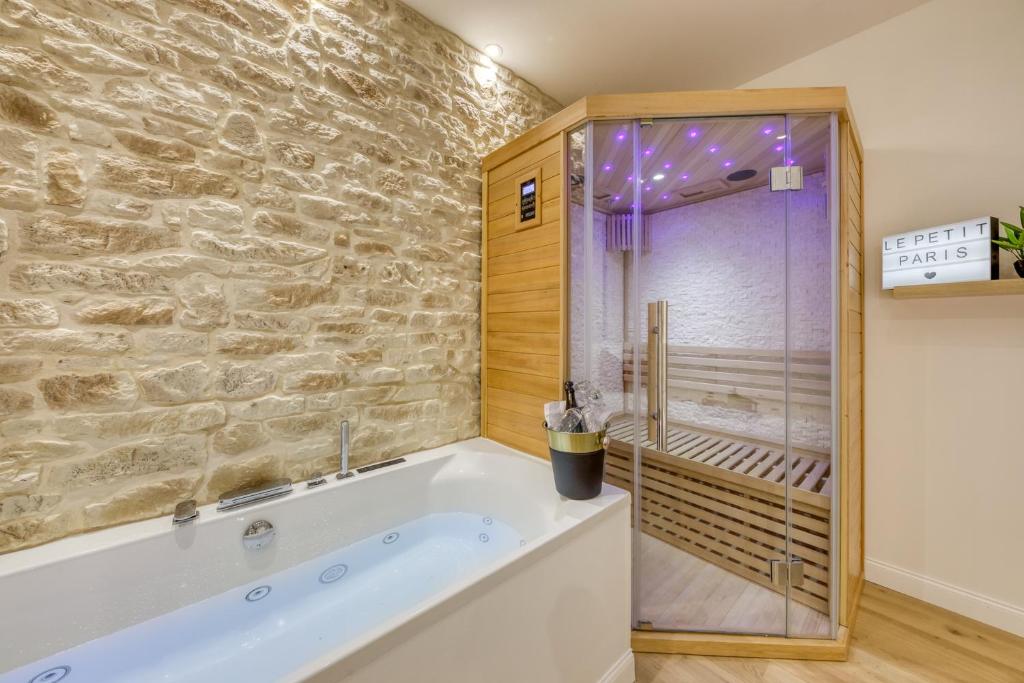 a bathroom with a tub and a stone wall at Le Petit Paris - Cocon & Spa & Sauna in Chartres