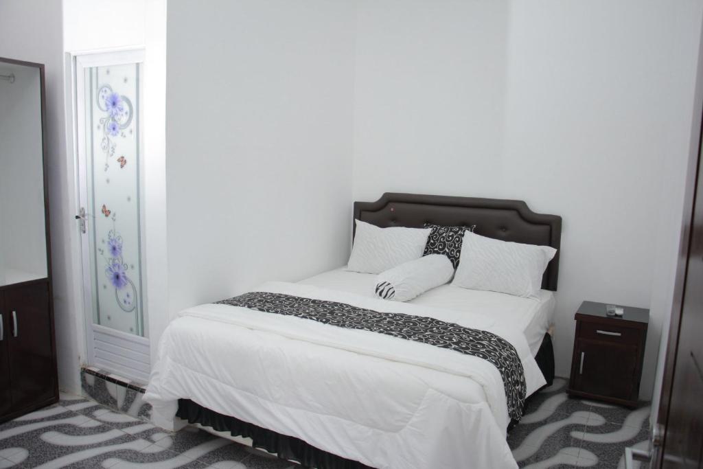 een slaapkamer met een bed met witte lakens en kussens bij Samar Wulu Guest House Syariah Mitra RedDoorz near Ketapang in Ketapang