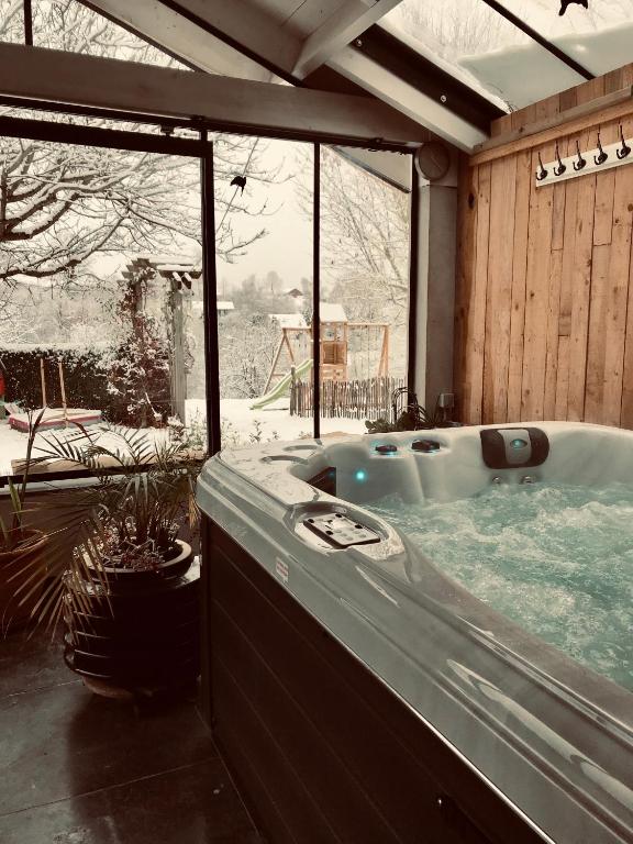 胡法利兹La Vieille Forge B&B的房屋内的按摩浴缸,外面下雪