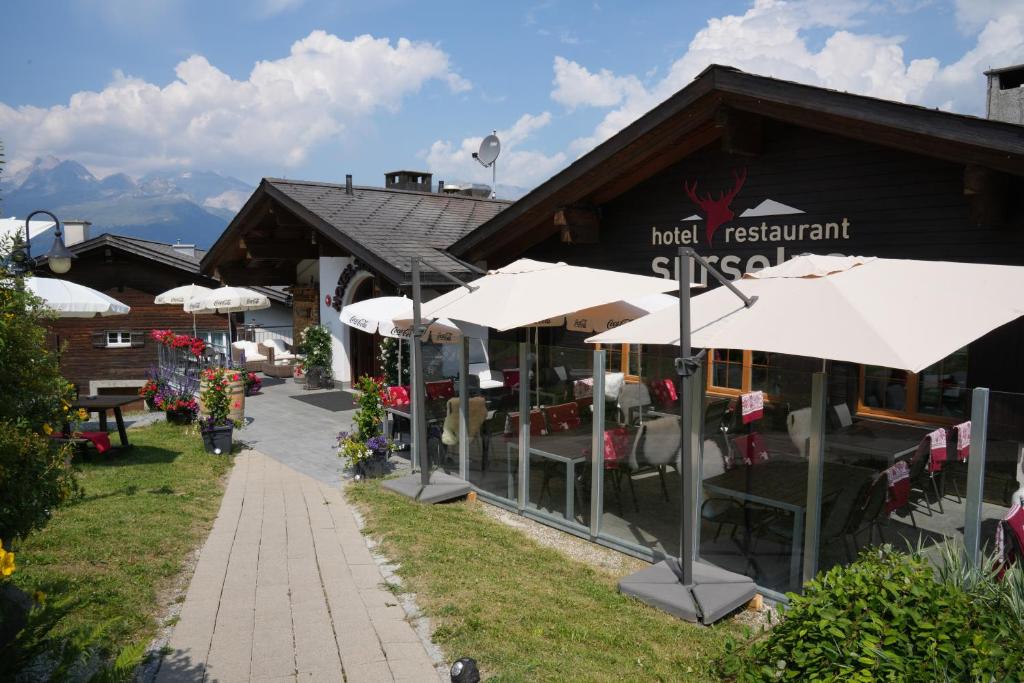 um restaurante com guarda-sóis brancos em frente em Hotel Surselva em Surcuolm