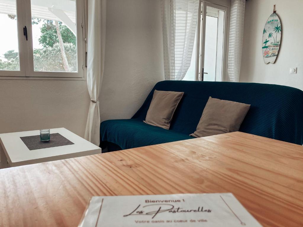 een woonkamer met een blauwe bank en een tafel bij Les Pastourelles in Capbreton