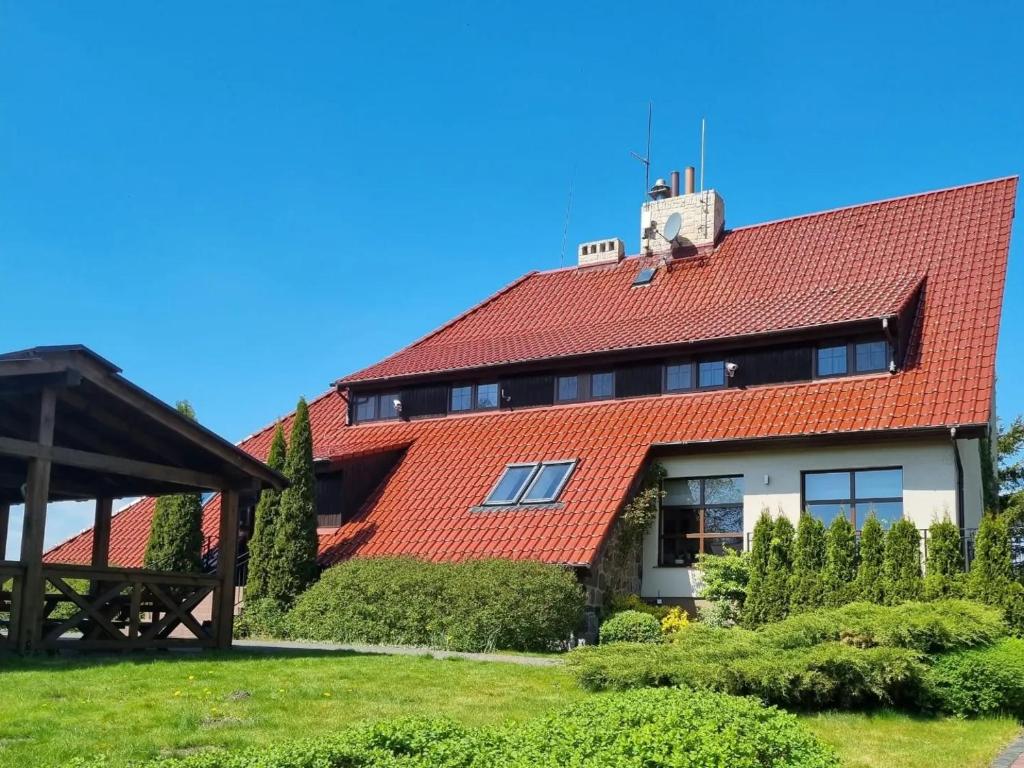 una casa con techo rojo en Zajazd Drogorad Restauracja i Noclegi en Mielno