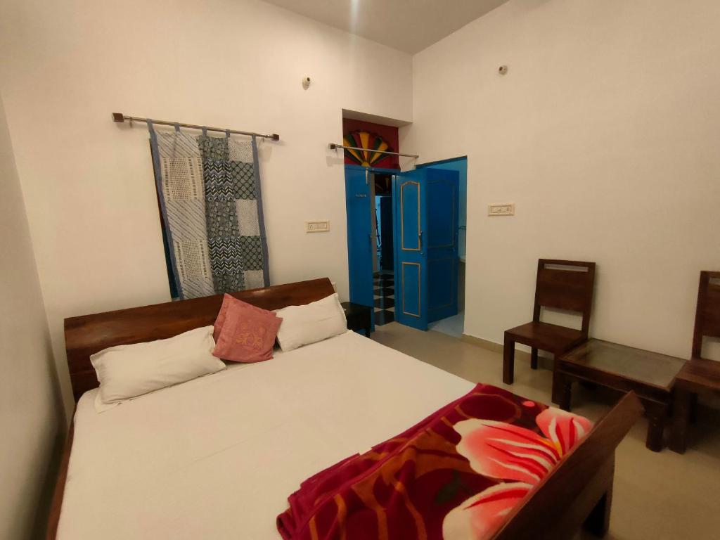 1 dormitorio con cama, silla y puerta azul en Bhavyam Heritage Guest House, en Jodhpur