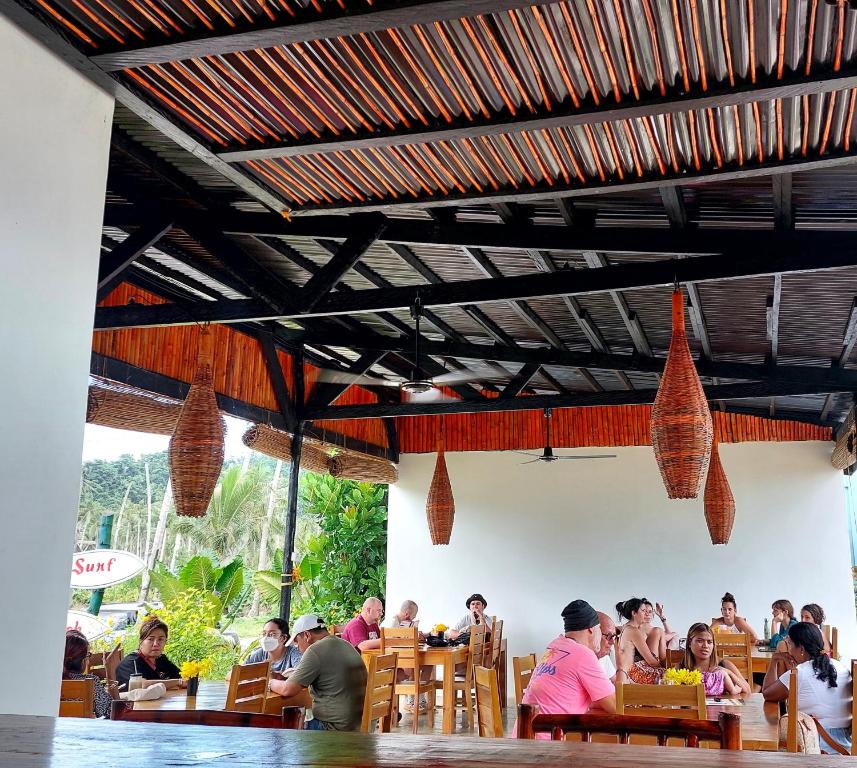 Bamboo Surf Beach في San Isidro: مجموعة من الناس يجلسون على الطاولات في المطعم