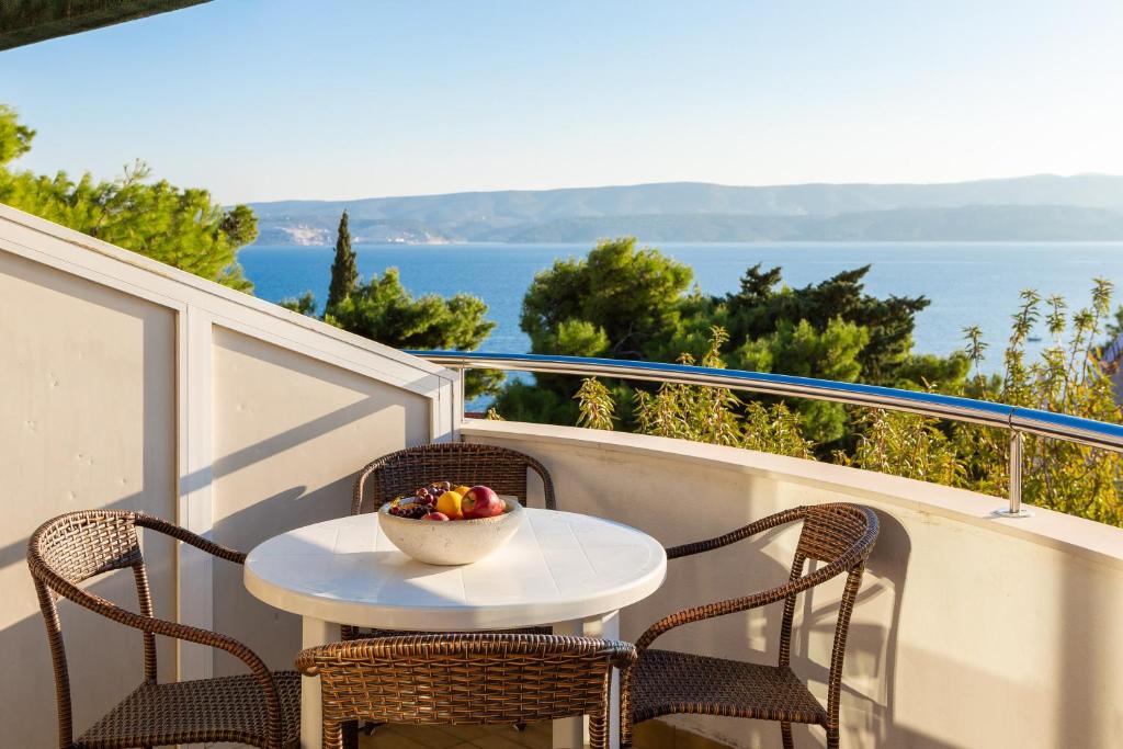 een tafel en stoelen op een balkon met een fruitschaal bij Villa Marko in Stanići