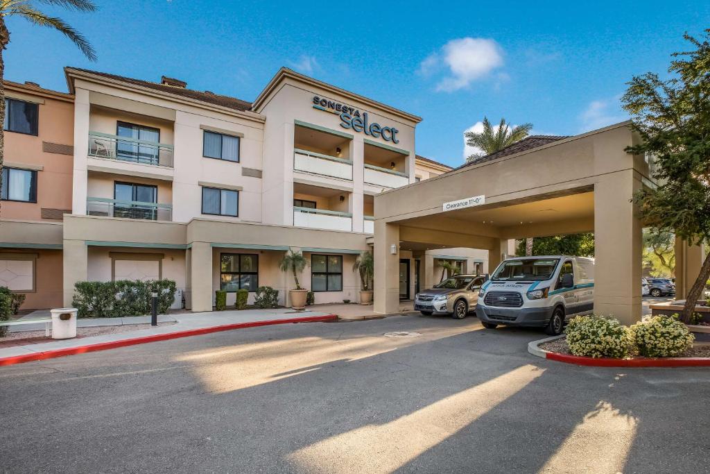 ein Hotel mit Autos auf einem Parkplatz in der Unterkunft Sonesta Select Phoenix Chandler in Chandler