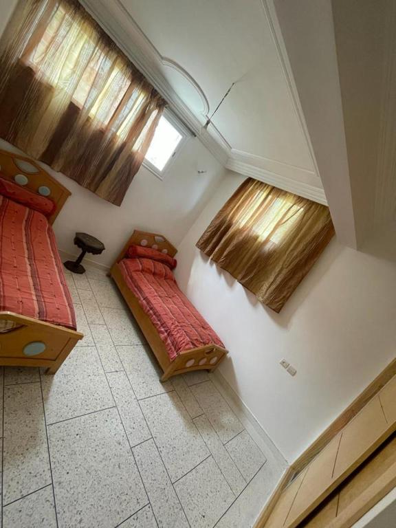 Cette chambre comprend 2 lits et 2 fenêtres. dans l'établissement Sous-sol villa, à Fès